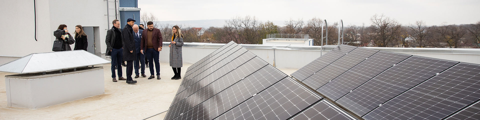 Mehrere Menschen stehen auf einem Dach neben einer Photovoltaikanlage 