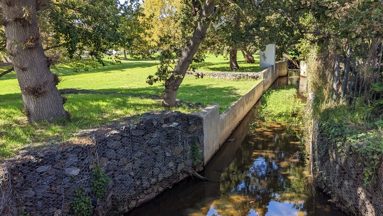 Ein sauberer Fluss fließt an einer befestigten Mauer vorbei, ein Beispiel für eine grau-grüne Infrastruktur zum Überflutungsschutz. Copyright: GIZ / Dirk Schaefer