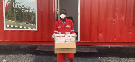 Ein Mann trägt Kartons aus einem roten Bürowagen.