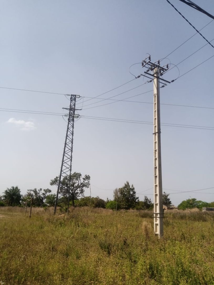Strommasten des öffentlichen Stromnetzes stehen in einem grünen, ländlichen Gebiet.