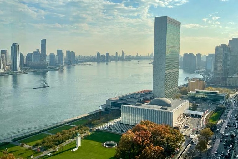 Das Büro der VN-Generalversammlung in New York mit dem East River und Wolkenkratzern im Hintergrund.