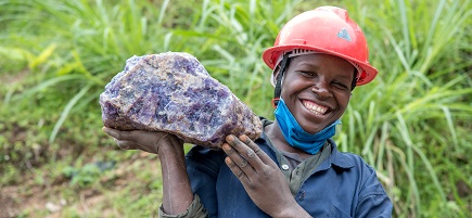 Eine Frau mit Schutzhelm hält einen Stein.