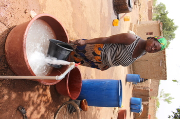 Eine Frau füllt Wasser für den Haushalt in Kanister. 
