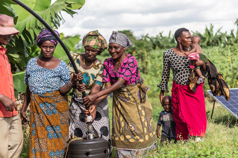 Eine Gruppe Frauen steht bei einer Schulung um ein Bewässerungssystem auf einem Feld.