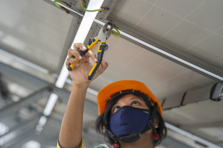 Eine Frau arbeitet an den elektrischen Leitungen einer Photovoltaikanlage. © GIZ BD/Rizwan Hasan