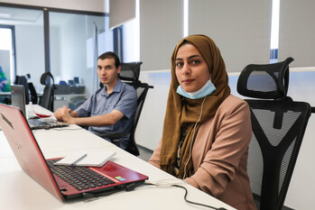 Zwei junge Menschen sitzen bei einer IT-Ausbildung hinter ihren Laptops. 