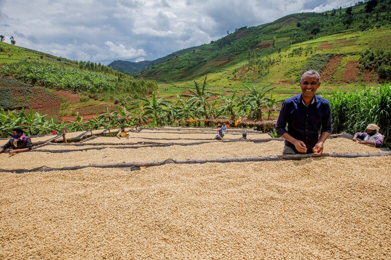 Mann vor hügeliger Landschaft bei der Trocknung von Kaffebohnen, Copyright: GIZ 