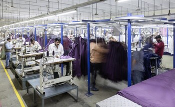 Arbeiter nähen in einer Textilfabrik Kleidungsstücke.