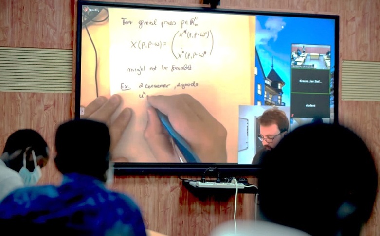 Ein Mann schreibt eine mathematische Formel, die auf einen Bildschirm übertragen wird.