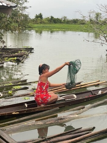 Frau mit Fischernetz in einem Boot.