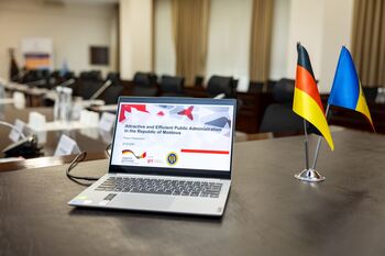 Ein Laptop, der den Projekttitel zeigt, steht auf einem Tisch neben der deutschen und moldauischen Flagge.