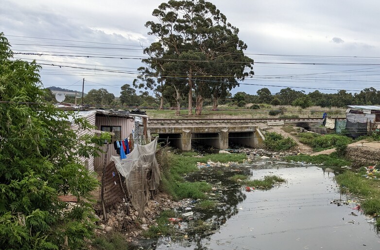 Am Ufer einer Überflutungszone neben einer informellen Siedlung schwimmt Abfall. Copyright: GIZ / Dirk Schaefer