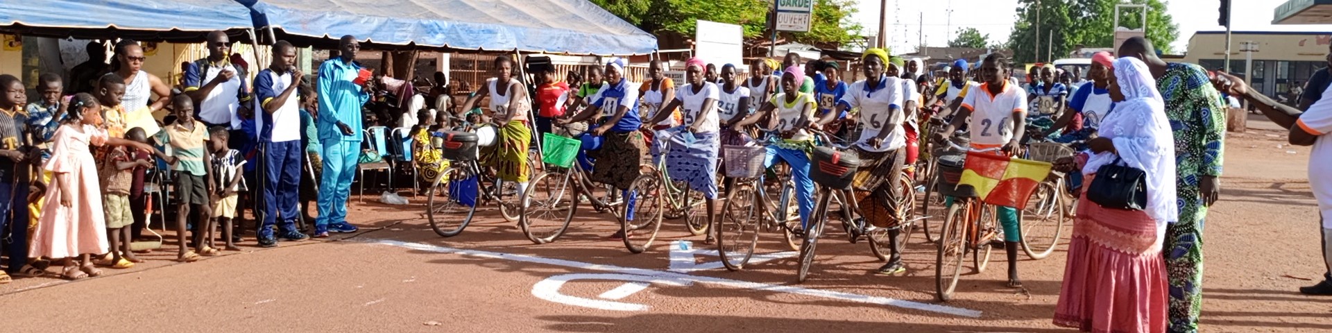 Binnenvertriebene und Frauen der Aufnahmegemeinde stehen bei einem Fahrradwettbewerb an einer Startlinie. © GIZ