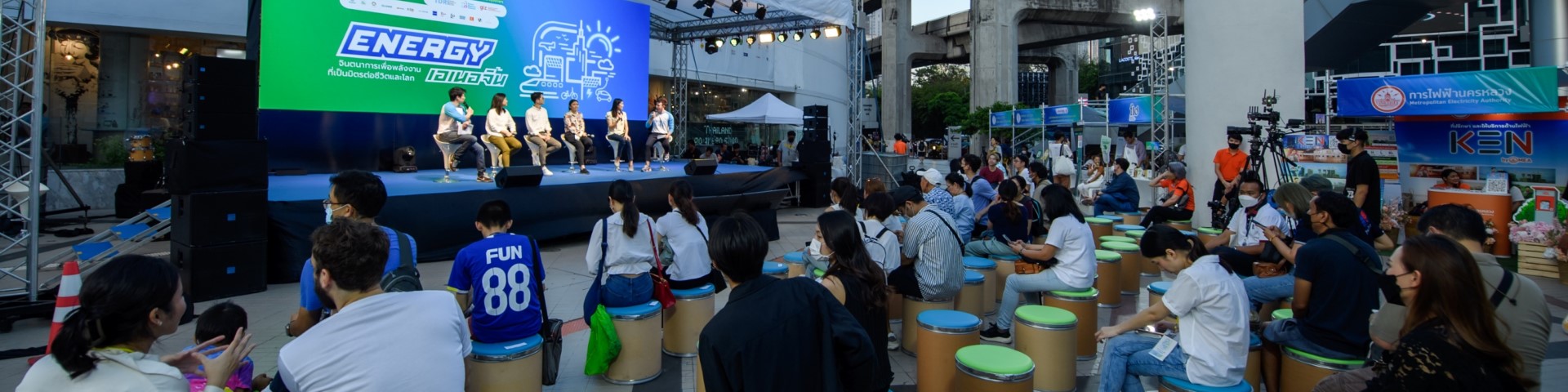 Sechs Personen sitzen bei einer Veranstaltung auf einer Bühne vor einem Publikum.