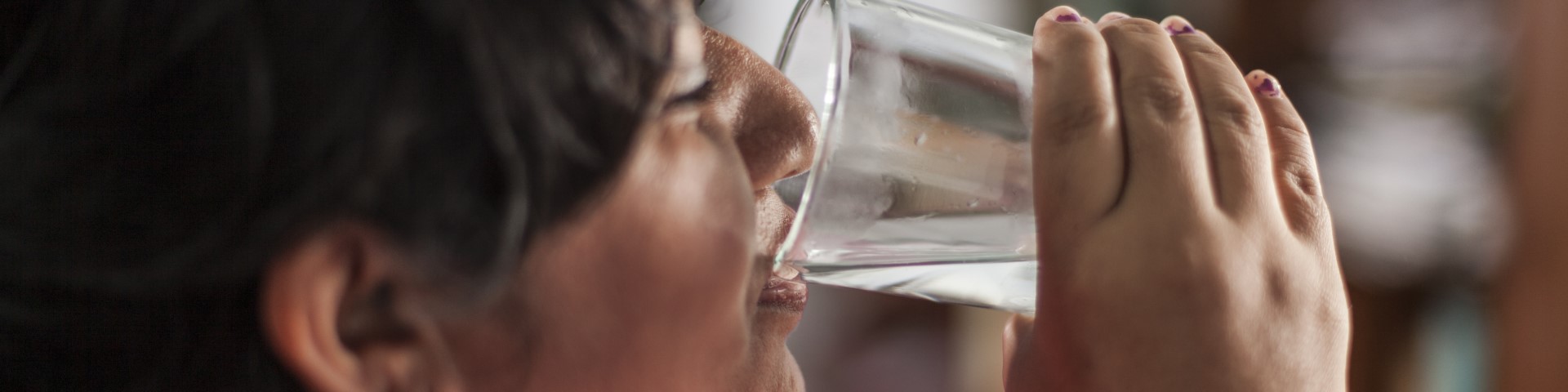 Eine Frau trinkt Wasser aus einem Glas.