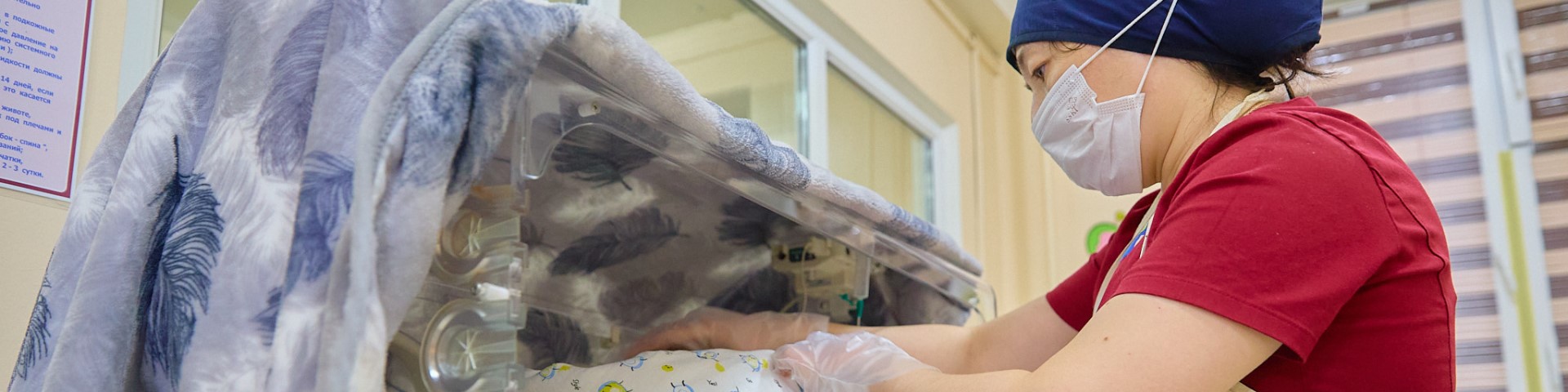 Eine Person in Schutzkleidung greift in einen medizinischen Inkubator. Copyright: GIZ/Stepanov Pavel