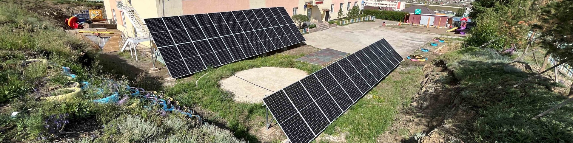 Auf der Grünfläche vor einem Wohnhaus stehen zwei PV-Solarpaneele.