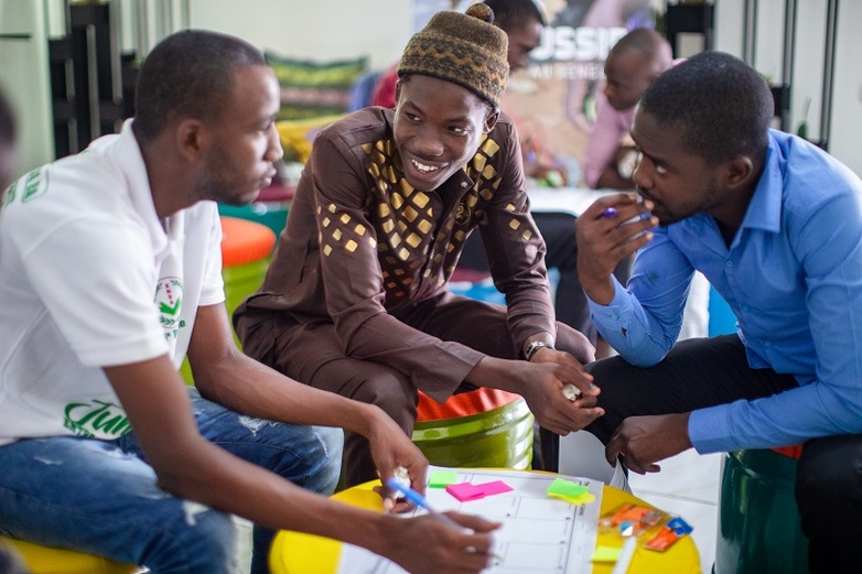 Drei Männer sitzen um ein Tabellendokument mit Notizzetteln herum und diskutieren im Rahmen einer Unternehmertums-Fortbildung in Dakar. Copyright: GIZ/Diallo.