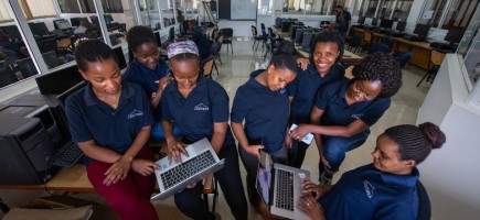 Eine Gruppe junger Frauen arbeitet an zwei Laptops.