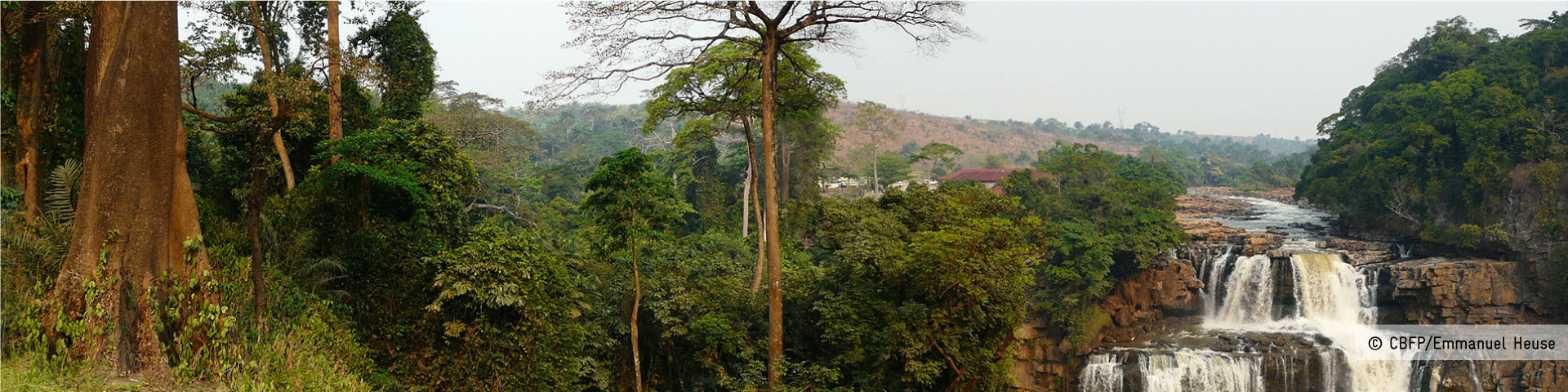 A hilly landscape in the Congo Basin with rainforest and a waterfall.