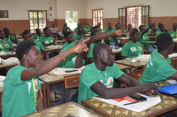 Young men and women in green T-shirts in a classroom.