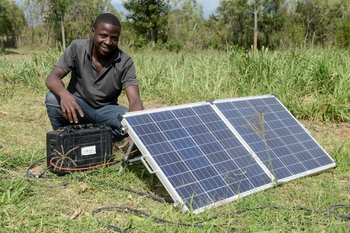 Une exploitante agricole travaillant dans un champ à proximité d’un système d’irrigation à énergie solaire. 