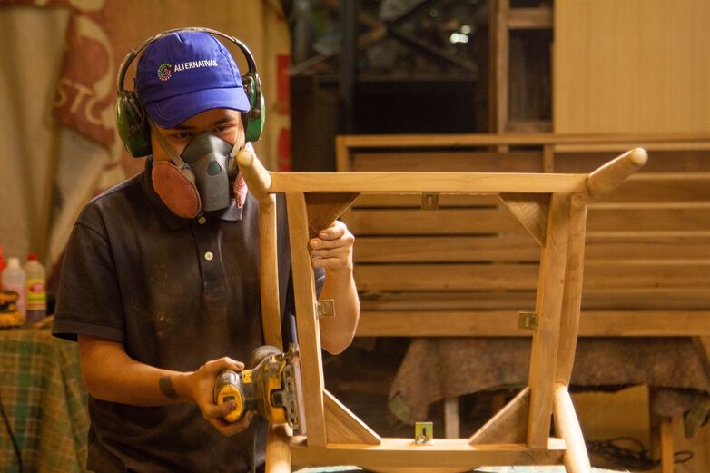 A person wearing a mask and working on a piece of wood.