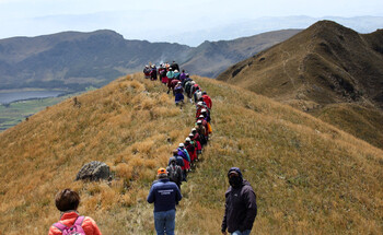 A group of people walk in single file across the Andean highlands.