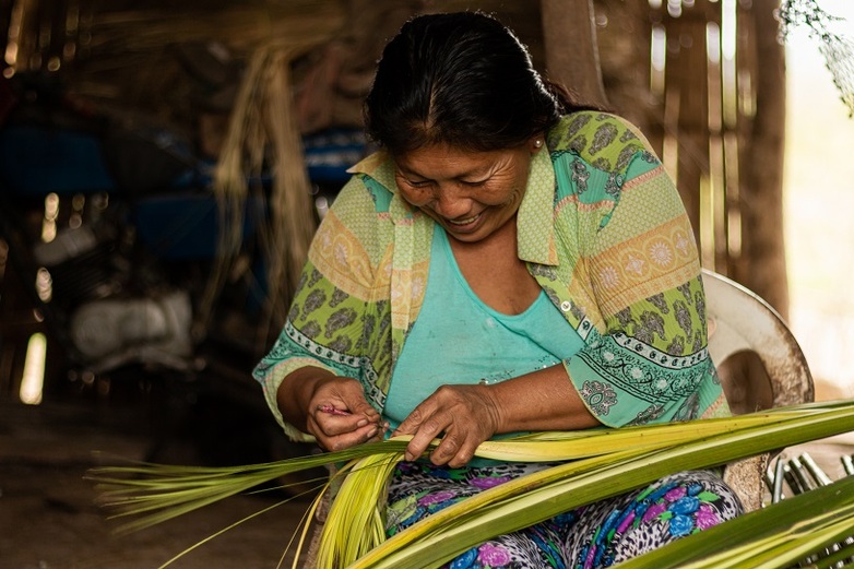 Una mujer tejiendo paja