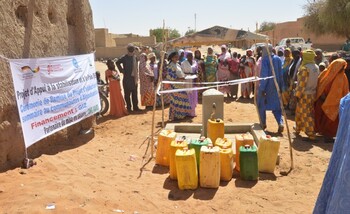 A large group of people with several canisters at a handover ceremony for the Aldjanabandia water supply (Gao).