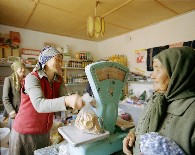 A saleswoman places goods on a scale.