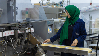 A woman working in a facility that produces plastic cutters and packaging.