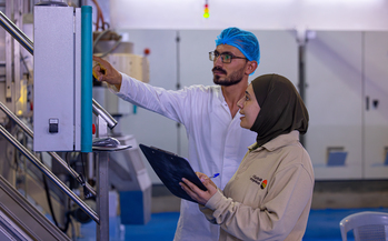 A man and a woman working at a machine used in food production.