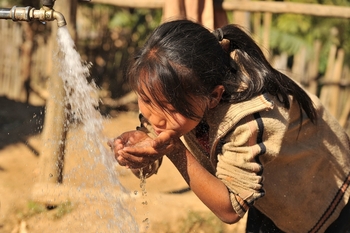 A young girl drinking water coming from a pipe. Copyright: GIZ