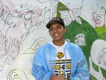 A young person in front of a mural