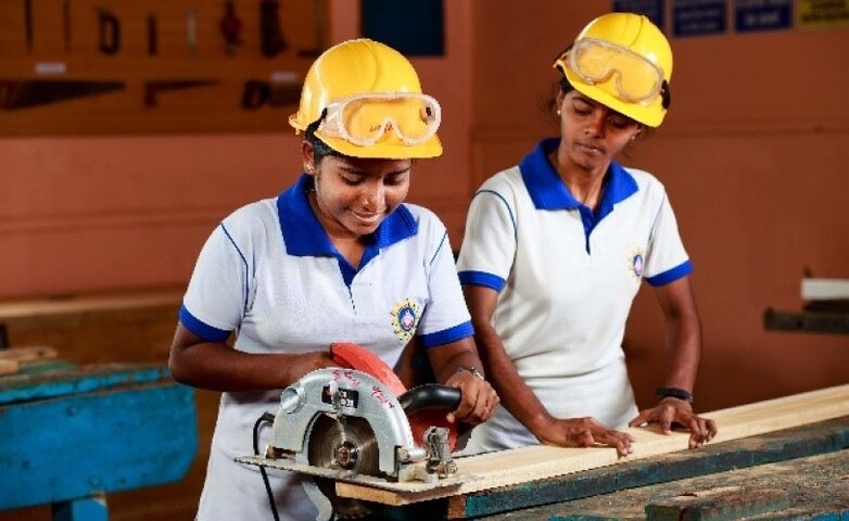 Two women working with an electronic saw