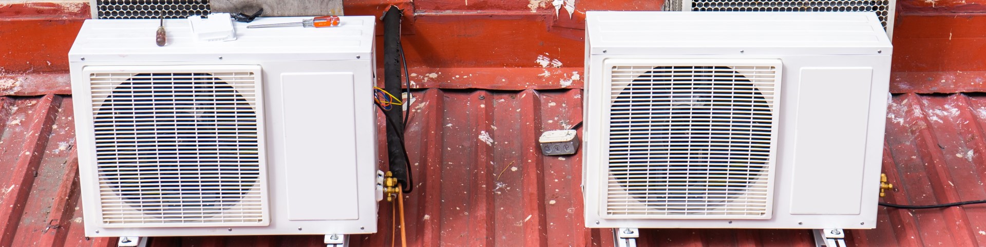 Two air conditioners on a red roof
