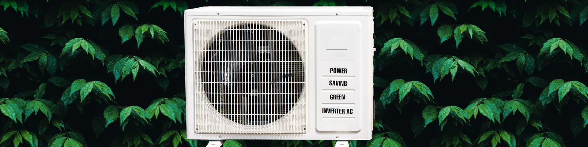An air conditioner positioned in front of green leaves.