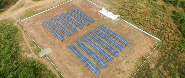 Douze rangées de panneaux solaires au milieu d’un paysage verdoyant. 
