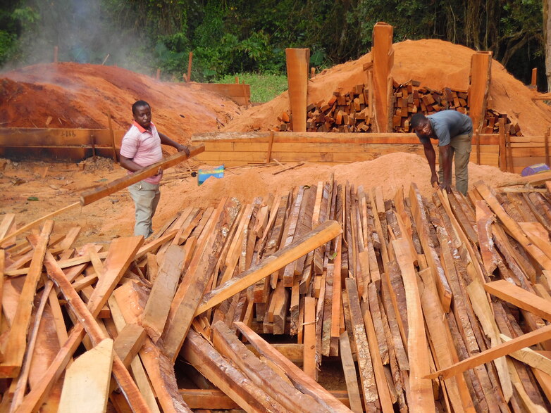 Deux hommes trient de longues poutres afin de valoriser les déchets de scierie pour la production de charbon de bois. Droits d’auteur : GIZ / ProFEC