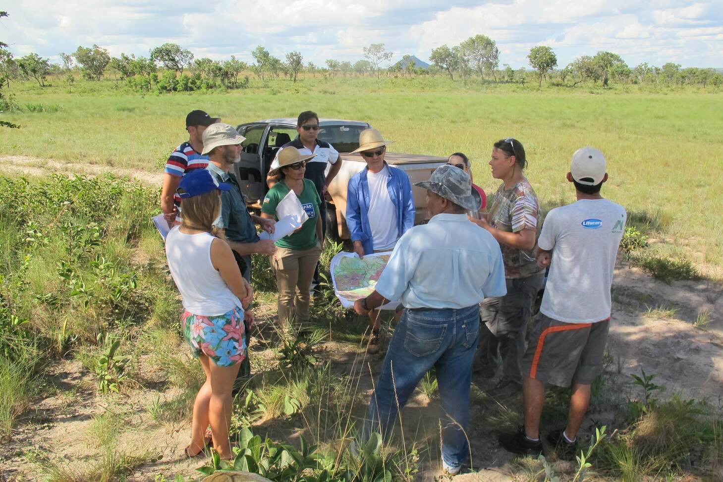 A group of people standing at the edge of a field; some are holding maps. Copyright: GIZ Brazil