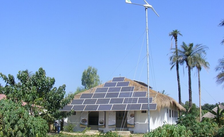 Solar panels on a house with a straw roof.