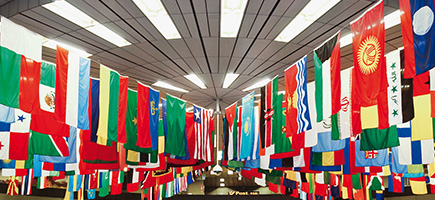 A room with a multitude of international flags hanging from the ceiling.