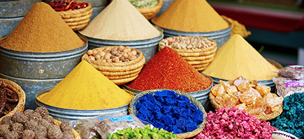Various colorful spices and food in baskets and bowls.