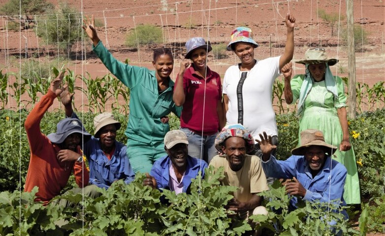 Young farmers stand together for a photo in their green garden and wave