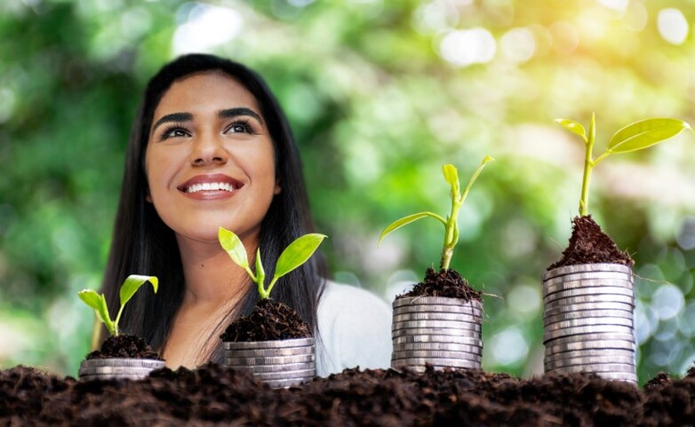 Una mujer situada detrás de plantas que simbolizan una recuperación económica verde