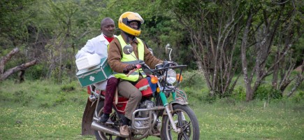 Two people with medical equipment on a motorbike.