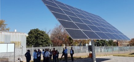 People standing under a large solar panel
