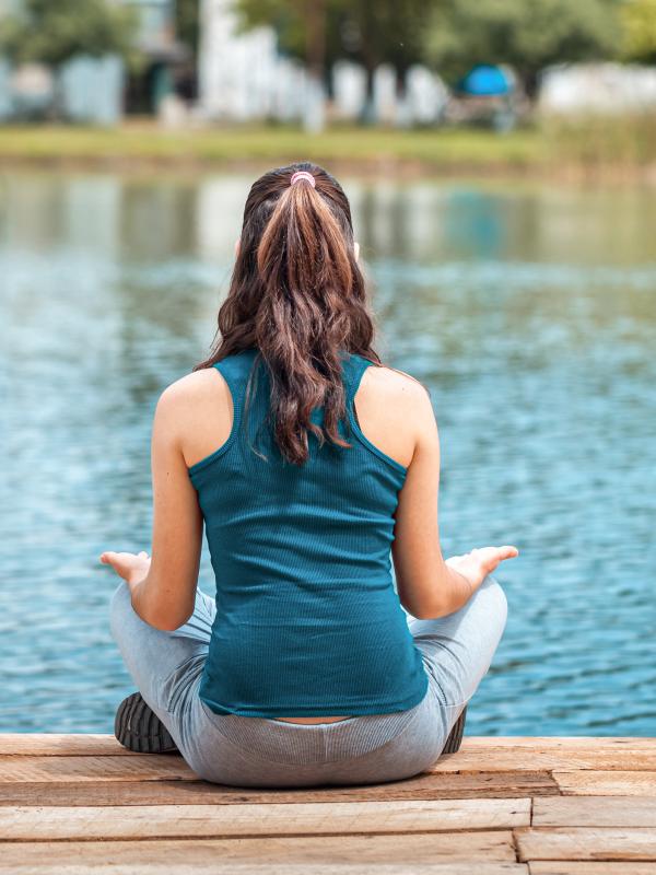 Frau im Lotussitz an einem See