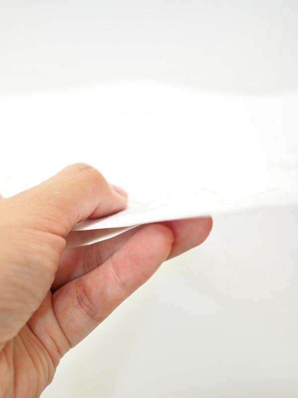 Eine Hand hält ein Blatt Papier.